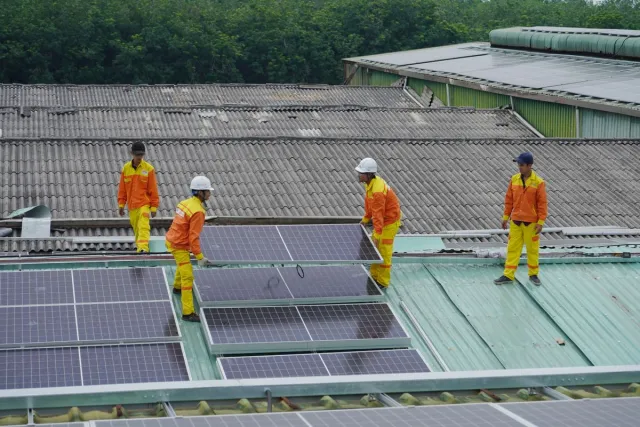 Stock reference: workers positioning solar panels on a roof.