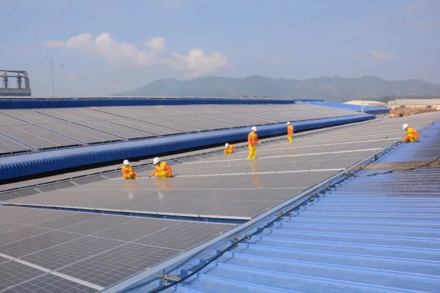Stock reference: technicians working across a large rooftop solar array.